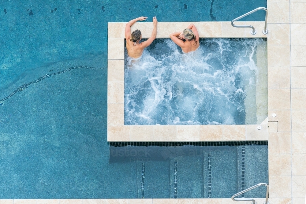 Looking down on two women relaxing in a bubbling spa - Australian Stock Image
