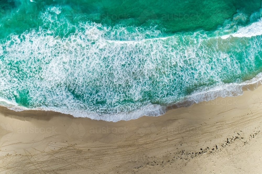 Looking down on waves crashing onto beach. - Australian Stock Image