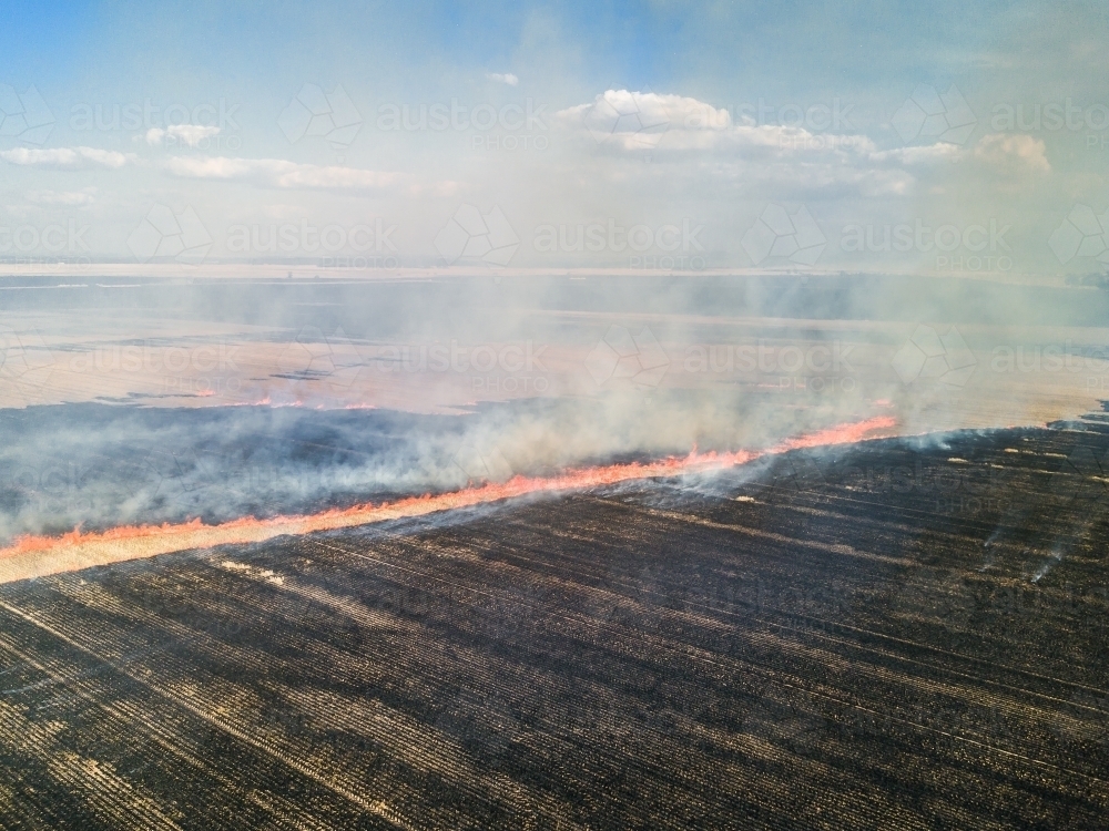 Looking down over a fire burning stubble in a paddock - Australian Stock Image
