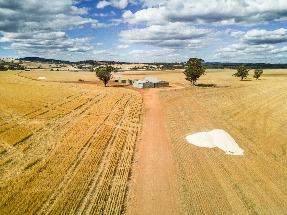 Looking down over a road in a paddock leading to farm sheds - Australian Stock Image