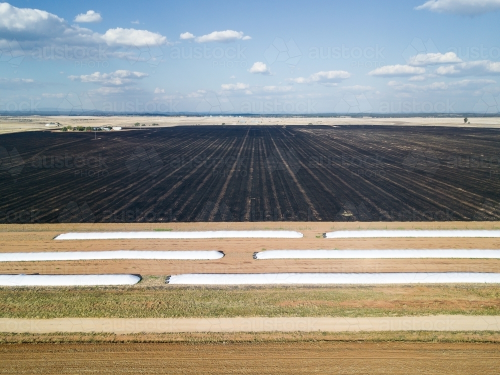 Looking down over grain storage pits and a burnt paddocks on a farm - Australian Stock Image