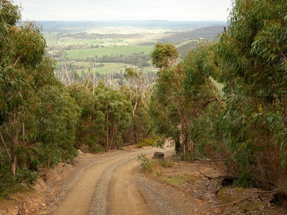 Looking Down Steep Gravel Road Toward Distant Farmland - Australian Stock Image
