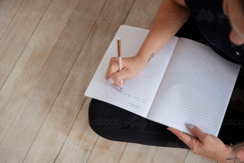 looking down woman journalling goal setting in yoga clothes - Australian Stock Image
