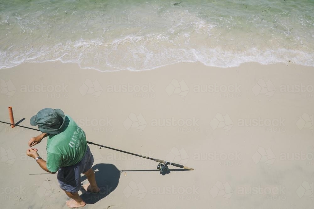 looking from above a fisherman preparing his line with bait - Australian Stock Image
