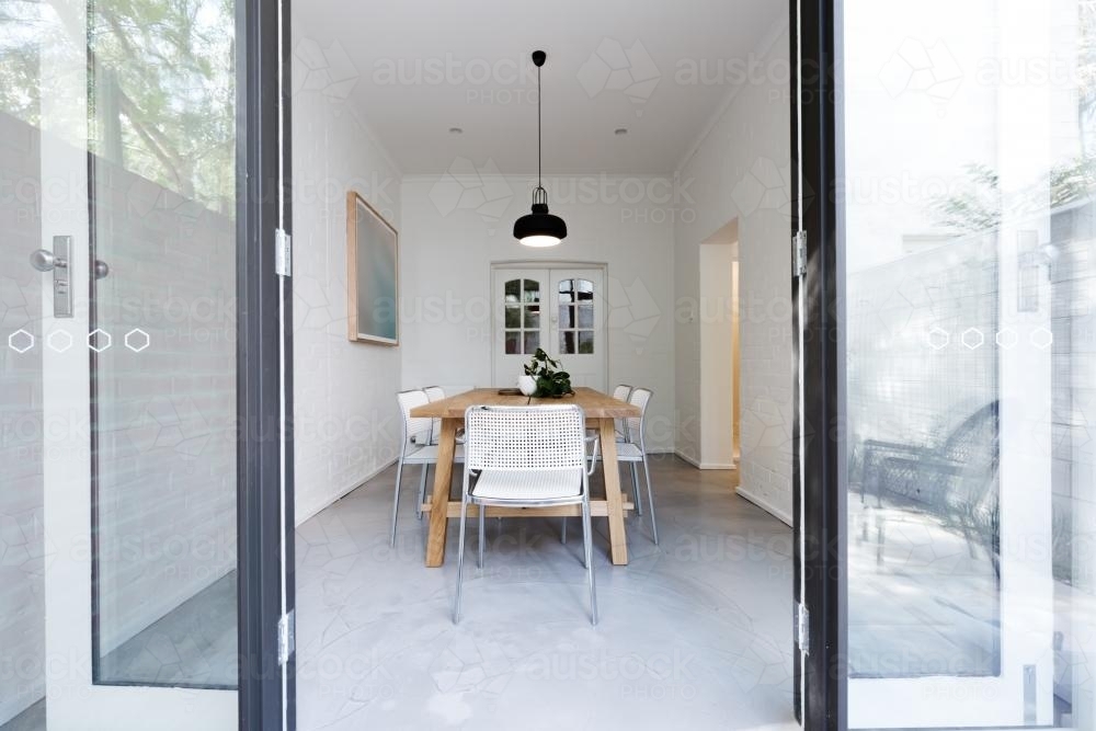 Looking into contemporary scandi styled dining room through french doors from courtyard - Australian Stock Image