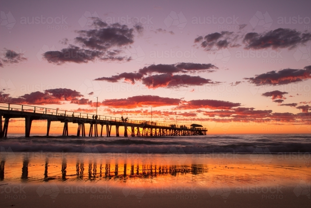 Looking out at a long wharf on the beach at sunset - Australian Stock Image