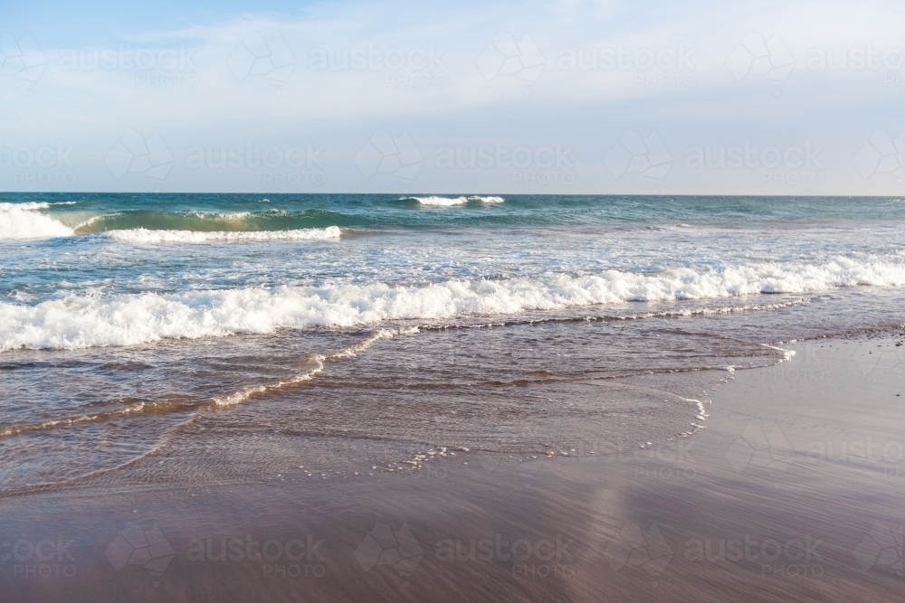 Looking out from beach at waves breaking in the ocean as the tide comes in. - Australian Stock Image