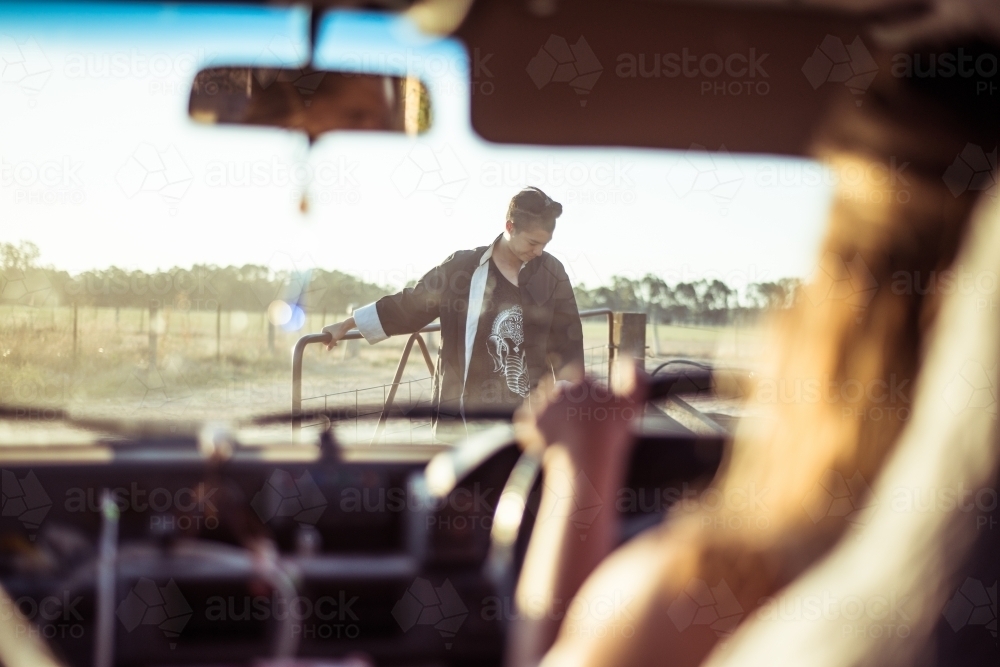 Looking out of car window to person holding open paddock gate - Australian Stock Image