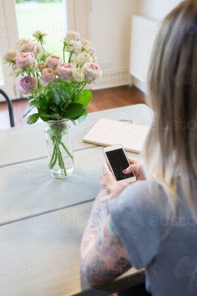 Looking over the shoulder of a girl using her mobile device at home - Australian Stock Image