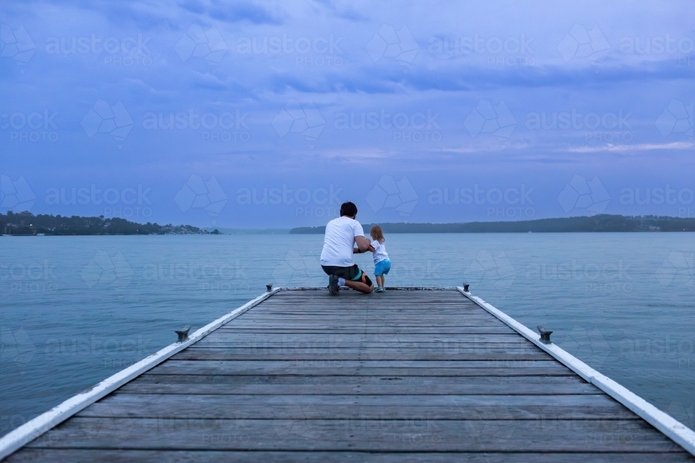 Looking over water from Warners Bay Public Jetty in dusk light at nightfall - Australian Stock Image