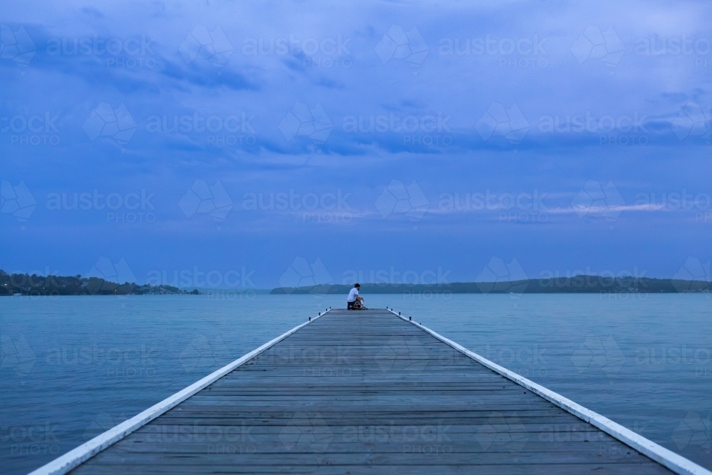 Looking over water from Warners Bay Public Jetty in dusk light at nightfall - Australian Stock Image