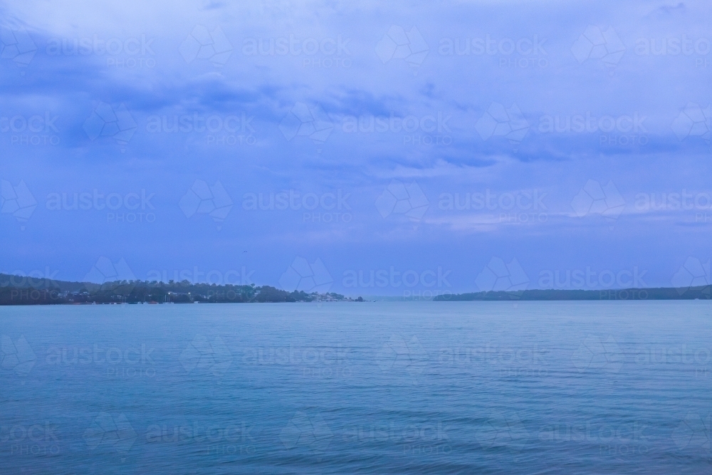 Looking over water from Warners Bay Public Jetty in dusk light at nightfall - Australian Stock Image