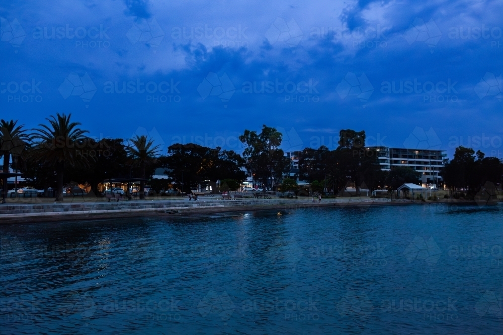 Looking over water from Warners Bay Public Jetty in dusk light at nightfall - Australian Stock Image