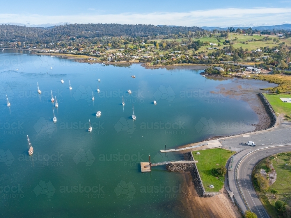 Looking own on yachts anchored in a river near a boat ramp. - Australian Stock Image