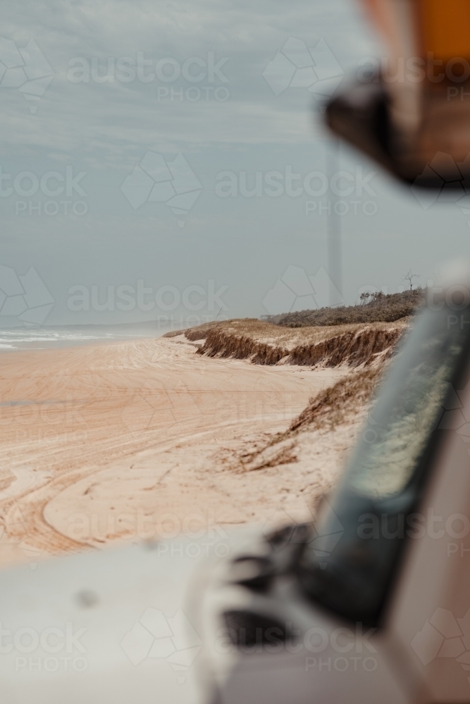 Looking past a 4WD to a sand dune and deserted Spit Fire Beach - Australian Stock Image