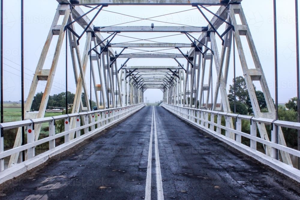Looking through and across white timber rural traffic bridge - Australian Stock Image