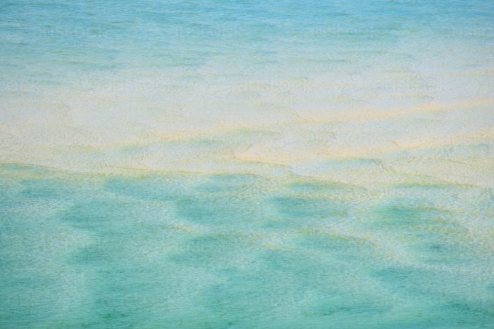 Looking through blue seawater at patterns in the sand - Australian Stock Image