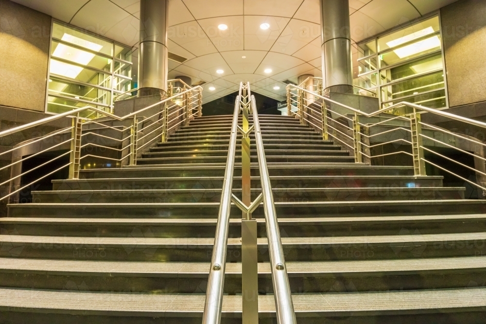 Looking up a staircase with stainless steel railings leading into a modern building - Australian Stock Image
