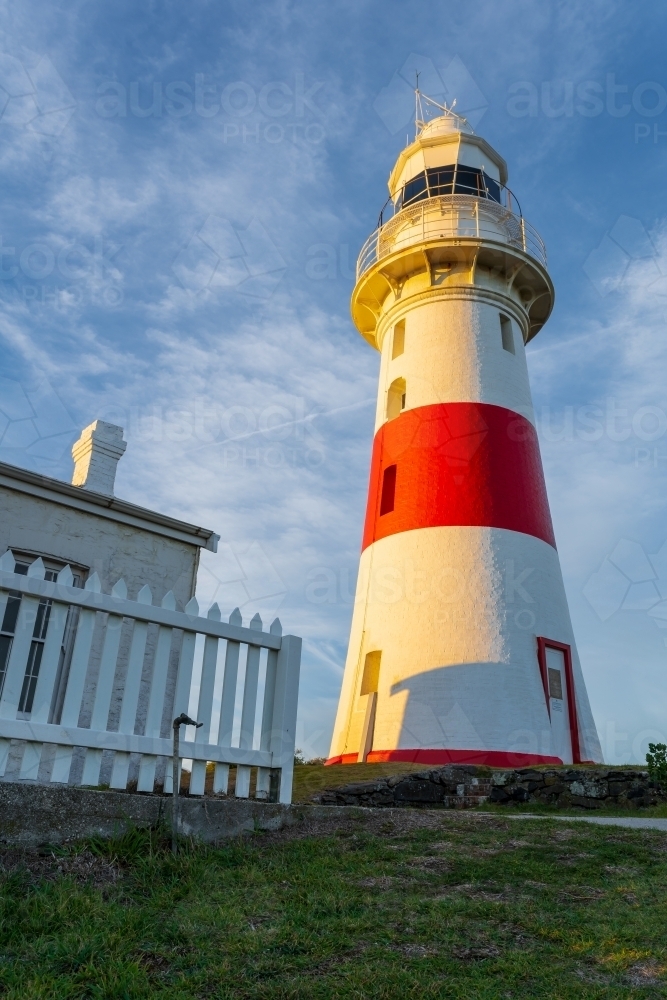 Looking up at a brightly painted lighthouse next to a fence - Australian Stock Image