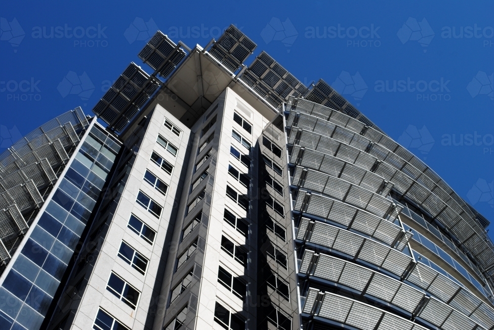 looking up at a modern office building against blue sky - Australian Stock Image