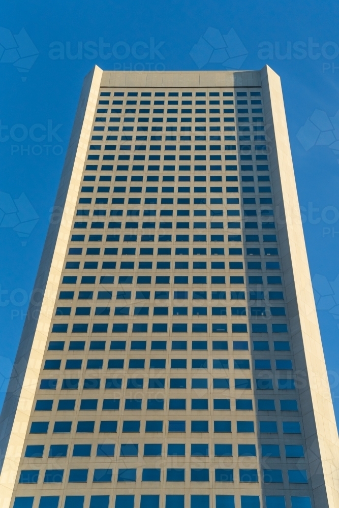 Looking up at a tall skyscraper with rows of uniform windows - Australian Stock Image