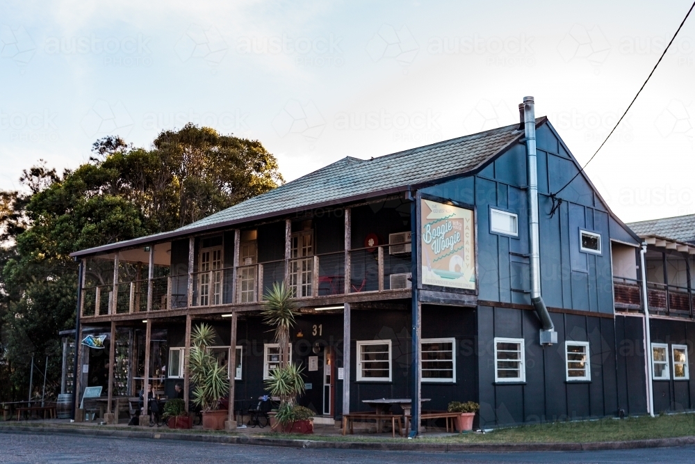 Looking up at a two storey dark blue building of an accommodation and cafe business in a small town. - Australian Stock Image