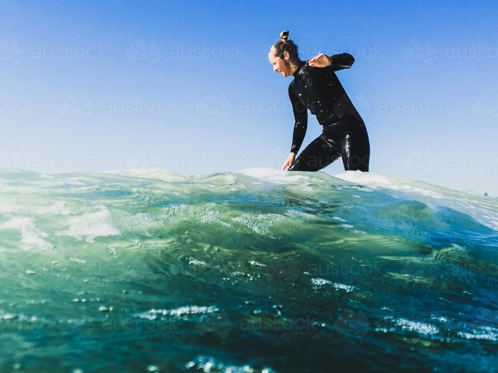 Looking up at a woman surfing on the other side of a wave - Australian Stock Image