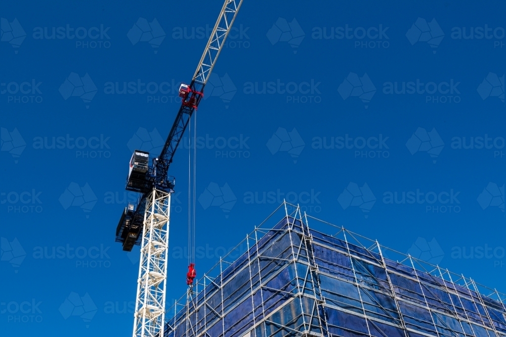 Looking up at hammer head crane and scaffolding with dark blue sky - Australian Stock Image