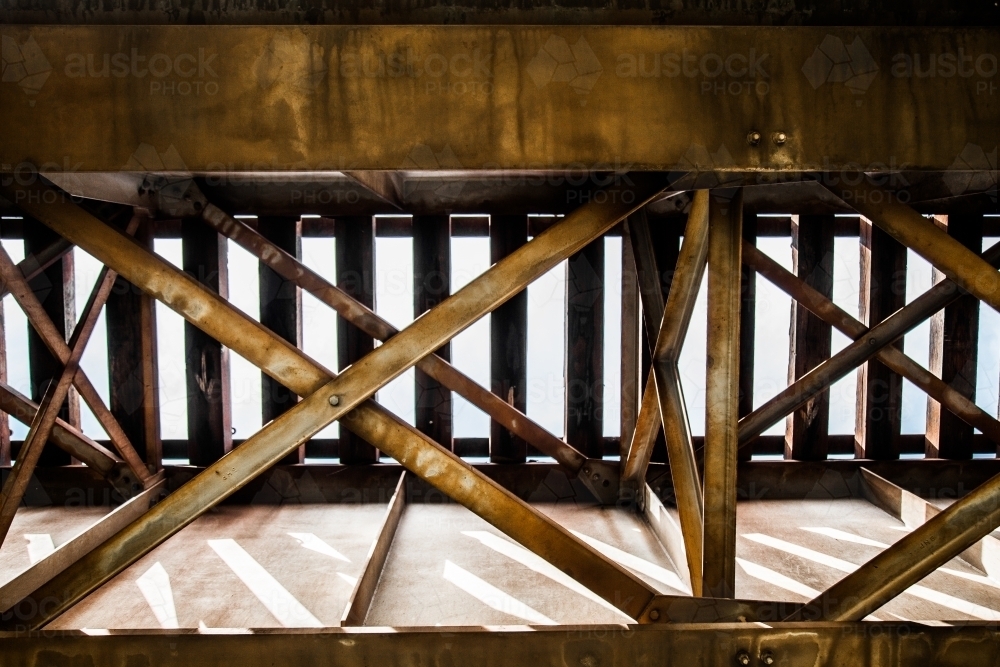 Looking up at metal structure underneath a train bridge - Australian Stock Image