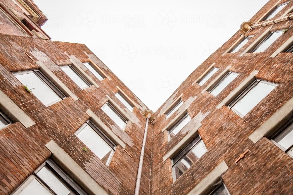 Looking up at old brick city buildings on overcast day - Australian Stock Image