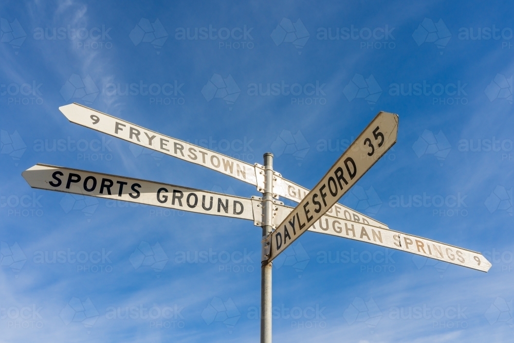 Looking up at  road sign with long directional arms, against a blue sky - Australian Stock Image