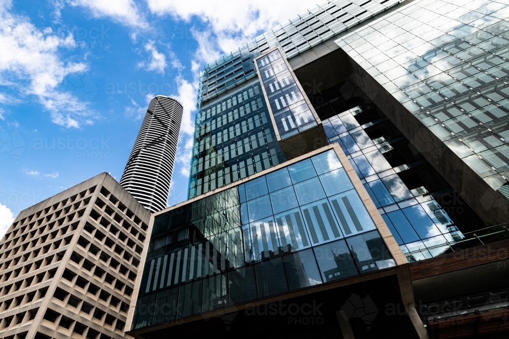 Looking up at skyscrapers with reflections, geometric patterns and converging lines to sky - Australian Stock Image