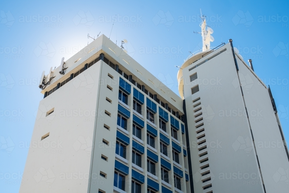 Looking up at tall building with sun shining behind building - Australian Stock Image