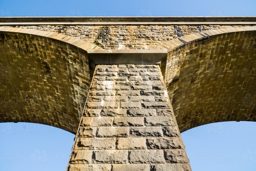 Looking up at the pillars and arches of a stone bridge - Australian Stock Image