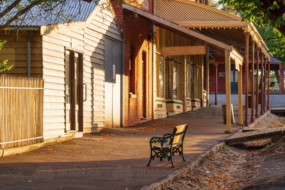 Looking up hill at a streetscape of old shop fronts with wide verandas - Australian Stock Image