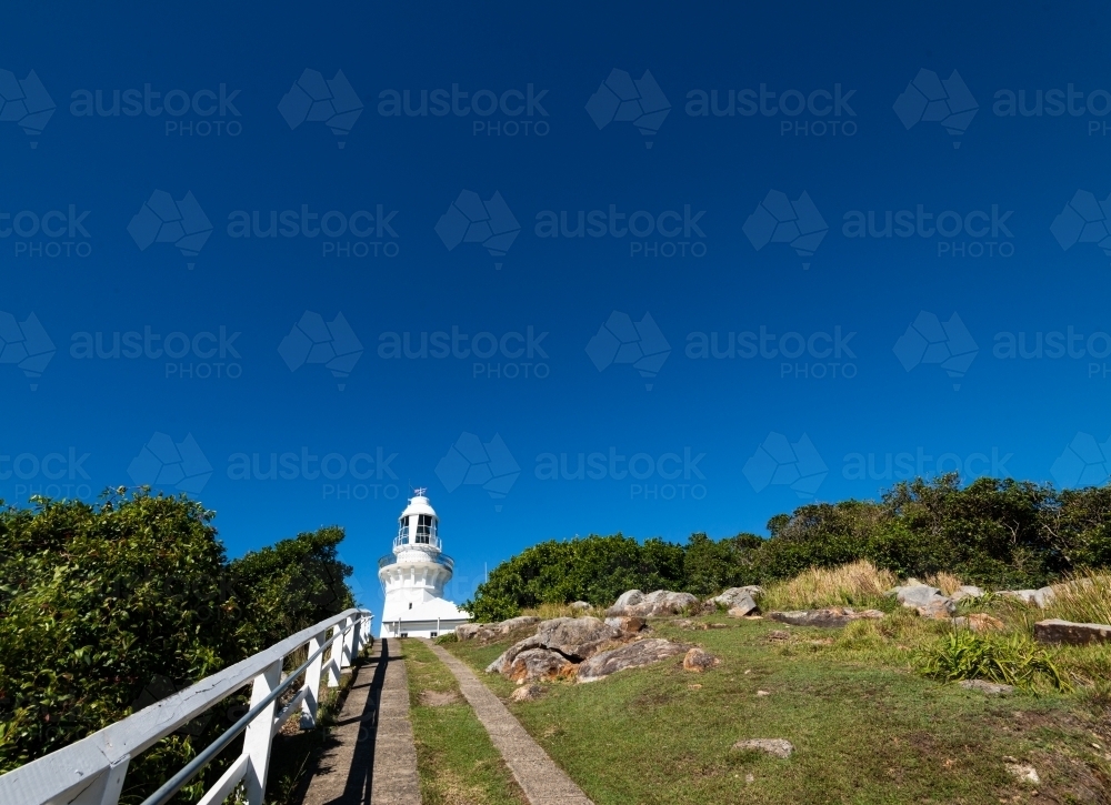 Looking up path to white lighthouse with deep blue sky - Australian Stock Image