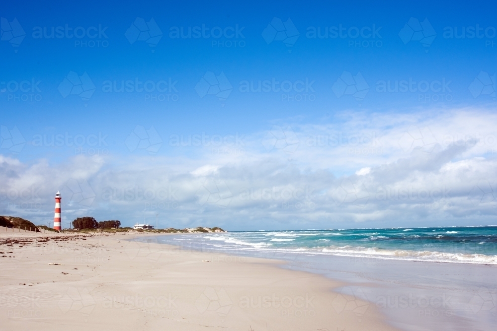 Looking up the beach and seeing a vintage lighthouse in the distance - Australian Stock Image