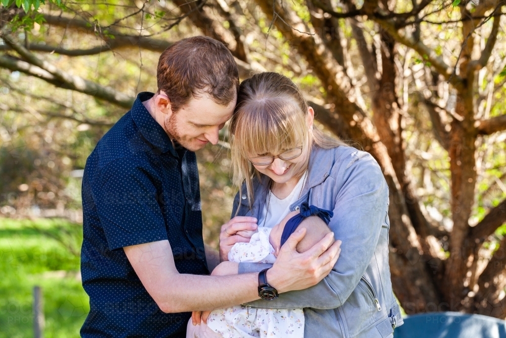 Loving first time parents doting on newborn daughter outside - Australian Stock Image