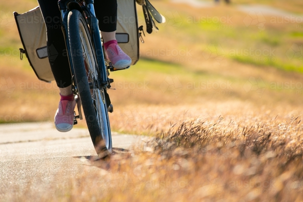 Low angle view of a female cyclist riding along a grassy lined bike path in Brisbane - Australian Stock Image