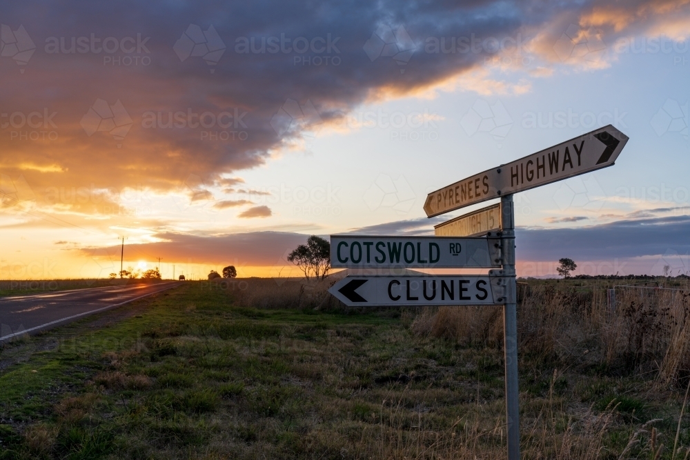 Low angle view of a road side sign on the side of a country road at sunset - Australian Stock Image
