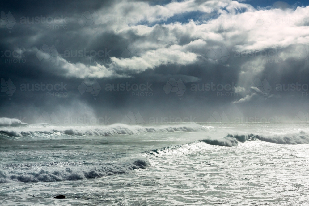 Low angled view of a dark stormy sky over large breaking waves - Australian Stock Image