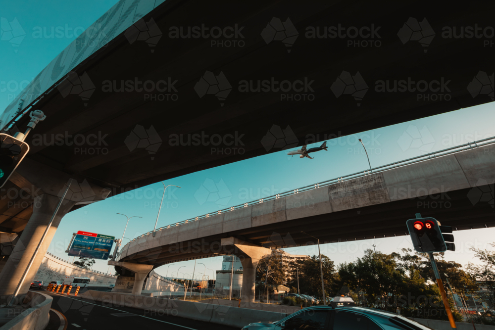Low flying plane visible in gap of overpass traveling to Sydney Airport - Australian Stock Image