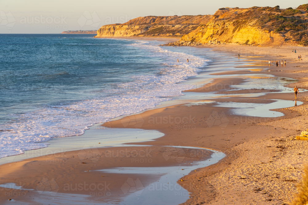 Low level aerial view of people walking around pools of water on a long sandy beach - Australian Stock Image