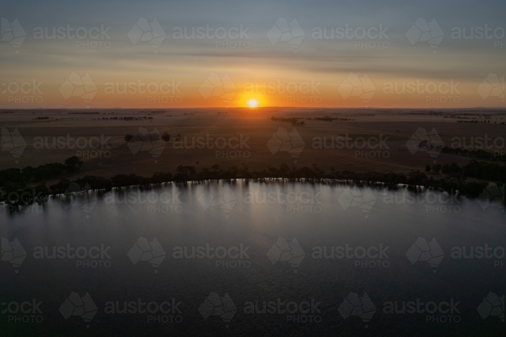 Low sun over landscape with lake in foreground - Australian Stock Image