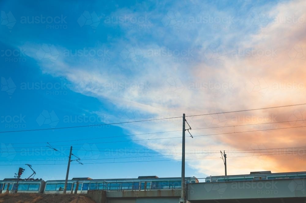 Low view of electric train passing with pretty sky behind - Australian Stock Image