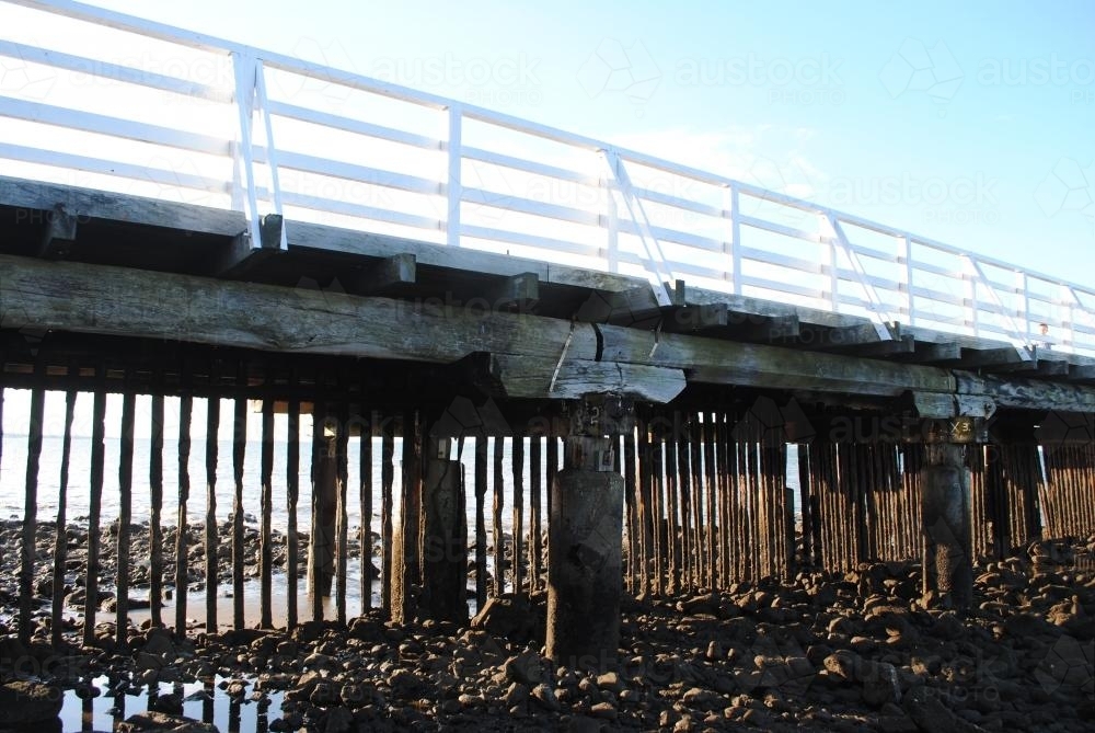 Low view of wooden pier at low tide - Australian Stock Image