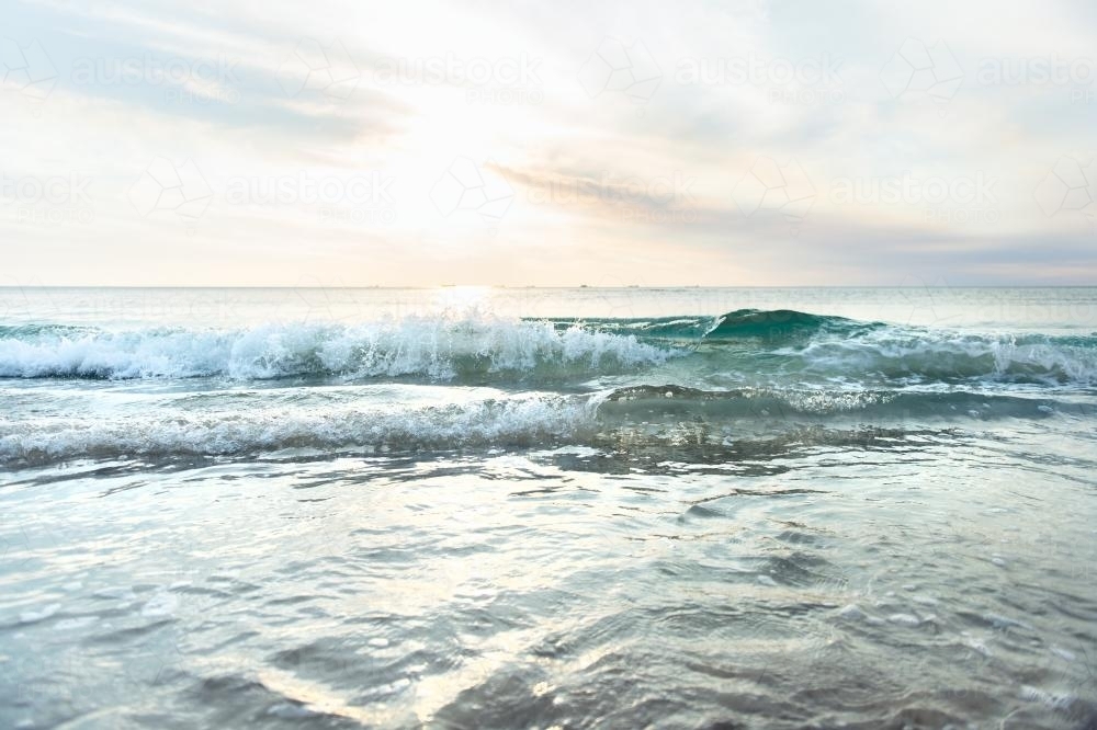 Low waves and pretty colours at the beach at sunset in summer - Australian Stock Image
