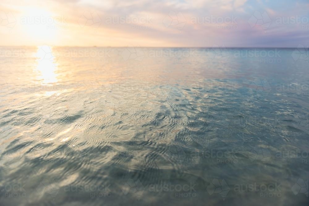 Low waves and pretty colours at the beach at sunset in summer - Australian Stock Image