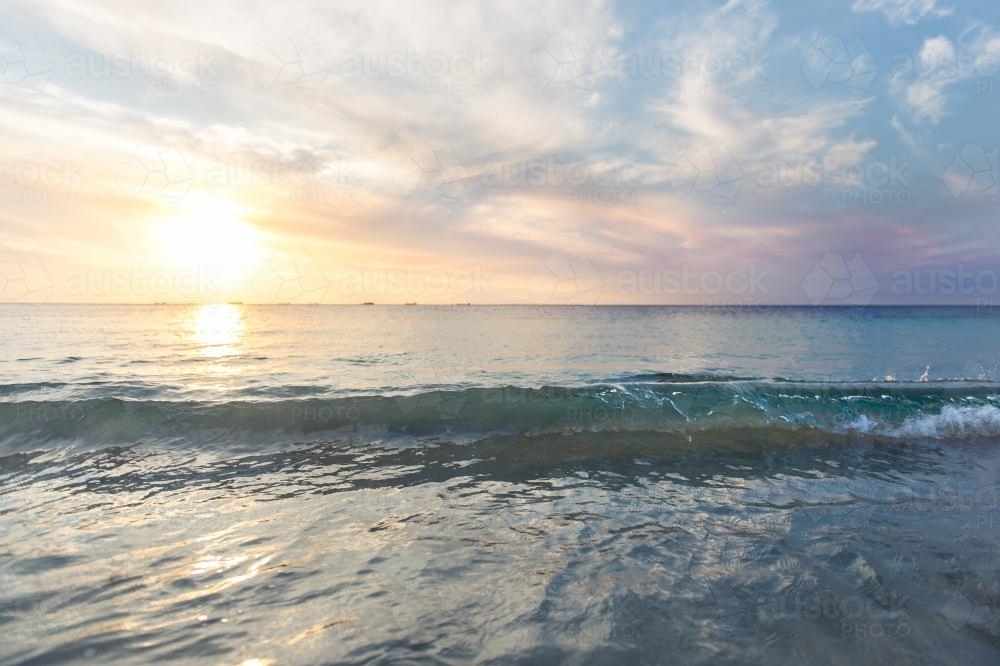Low waves and pretty colours at the beach at sunset in summer - Australian Stock Image