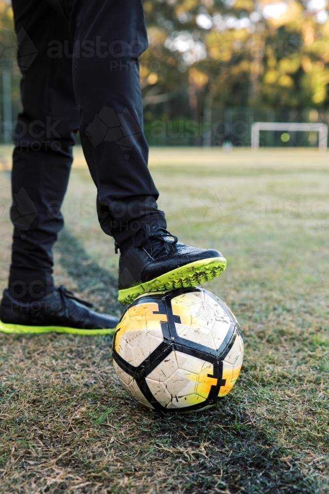 Lower extremity shot of standing on the field, stepping the soccer ball with one foot - Australian Stock Image
